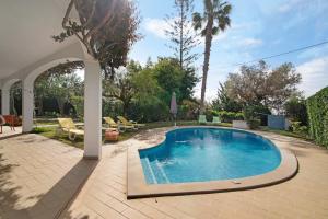 a swimming pool in a backyard with an archway at Casa da Oliveira in Loulé