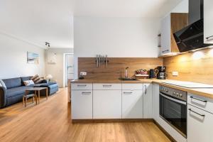 a kitchen with white cabinets and a living room at Snorrum Wohnung 7 in Husby +8 photos