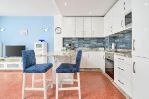 a kitchen with white cabinets and blue chairs at Torresol 208 in Nerja