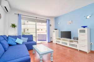 a living room with a blue couch and a tv at Torresol 208 in Nerja