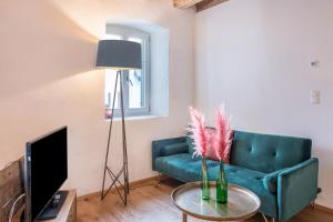 a living room with a green couch and a tv at Eichhof Apartment Thymian in Termeno