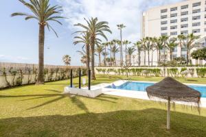 a resort pool with palm trees and a building at Torresol 208 in Nerja