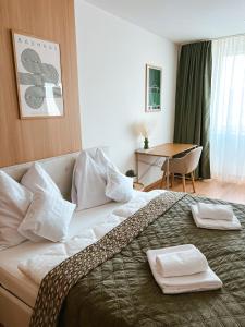 a hotel room with a bed with two towels on it at Bloom Olive Apartment in Trenčín