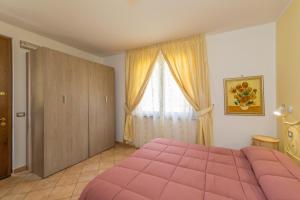 a bedroom with a pink bed and a window at Il Girasole - Cappero in Venturina Terme +23 photos
