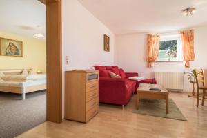 a living room with a red couch and a table at Ferienwohnung Marschall in Achberg