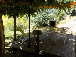 a table and chairs on a wooden deck with a grill at Le Mas in Arles-sur-Tech