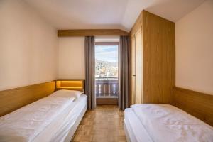 two beds in a room with a window at Rosalpina Apt 4 in San Vigilio Di Marebbe