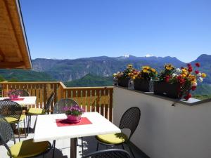 a balcony with tables and chairs with mountains in the background at Kristallhof Fewo Bergblick in Caldaro
