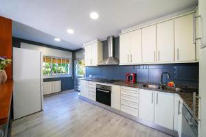 a kitchen with white cabinets and a blue wall at Villa Mar in Teià