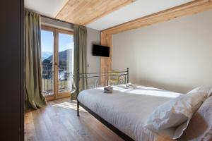 a bedroom with a bed and a large window at Casa Ronden Mortirolo in Mazzo di Valtellina