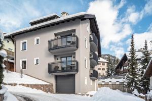 a white building with two balconies on it in the snow at La Grambla App Sella 1 in Santa Cristina Gherdëina