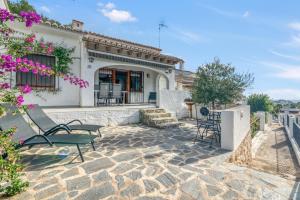 a patio of a house with chairs and flowers at Casa Julieta in Benitachell