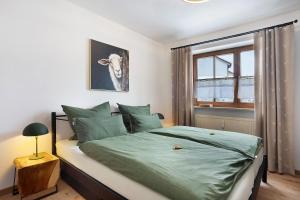 a bedroom with a bed with green sheets and a window at Ferienwohnung Vilstalstüble in Pfronten