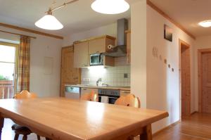 a kitchen with a wooden table with chairs and a stove at Ferienwohnungen Krapfenalm in Wagrain