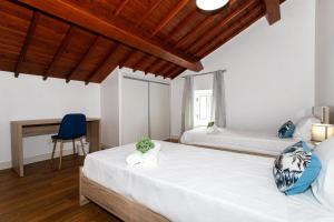 a bedroom with two beds and a desk at Oásis Fonte Grande in Santo António