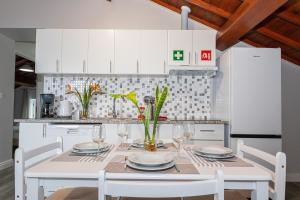 a white kitchen with a white table and chairs at Oásis Fonte Grande in Santo António
