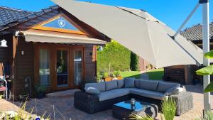 a patio with a couch and a large umbrella at Ferienhaus Burg Celle in Celle