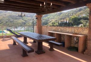a picnic table and benches on a patio with a view at Casa Olivia in Cómpeta