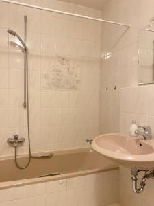 a bathroom with a sink and a shower and a tub at Ferienwohnung Starnberg in Starnberg +8 photos
