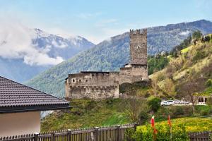 an old castle on a hill with mountains in the background at Ferienwohnungen Zwick Spinei in Malles Venosta +9 photos