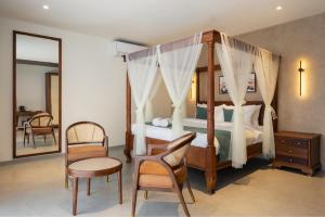 a bedroom with a canopy bed with a chair and a table at Olive Woods in Chinnakanal