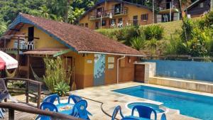 una piscina con sedie blu accanto a una casa di Waldhaus - A Pousada do Remo a Peruíbe