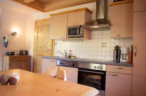 a kitchen with a stove and a wooden table at Ferienwohnungen Krapfenalm in Wagrain +30 photos