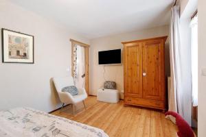 a bedroom with a bed and a chair and a television at Appartamenti Pila Vacanze 2 in Gressan