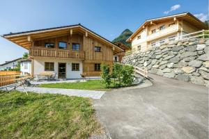 a large wooden house with a stone wall at Waldchalets & Ferienwohnungen Allgäu in Burgberg