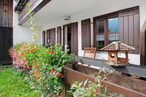 a porch of a house with flowers and a bird house at Ferienwohnung Reindler in Fischen