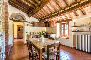 a kitchen and dining room with a wooden table and chairs at Appartamento Gemma Bianca-tavoleto in Castiglione dʼOrcia +27 photos