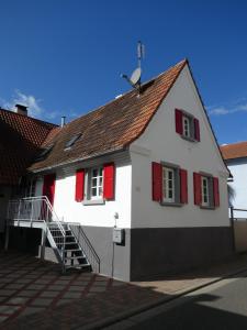 a white house with red shutters and a staircase at Ferien- und Gästehaus Jockgrim in Jockgrim
