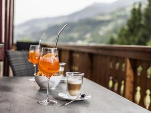 two glasses of drinks on a table on a balcony at Wolfbachgut - Ferienwohnung 1 in Taxenbach