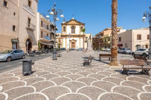 a city street with benches and a clock tower at Sole e Amore in Casteldaccia