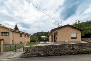 a house with a stone wall next to a building at Susurros de río in Ocejo