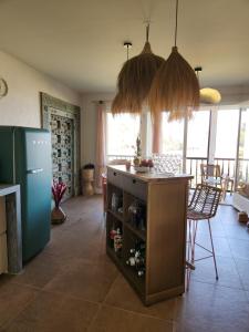 a kitchen with a refrigerator and a table with bottles at Le Topaze in Grimaud
