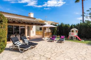 a patio with chairs and an umbrella and a playground at Casa Arturo in Sa Coma