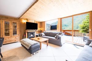 a living room with couches and a fireplace and a tv at Chalet Delphine Luxe, Ski aux pieds in Les Bruyères