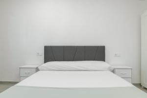 a bedroom with a white bed with white sheets at Apartamento Ajm in Barbate