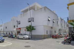 a white building with cars parked in a parking lot at Apartamento Ajm in Barbate