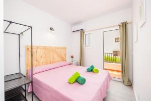 a bedroom with a pink bed with two green pillows on it at Gran Sol Family 4 in Felanitx +23 photos