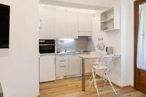a kitchen with white cabinets and a table and chairs at Super Mini Appartamento Lanzada in Lanzada