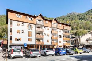a large building with cars parked in a parking lot at Super Mini Appartamento Lanzada in Lanzada