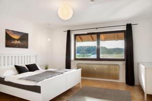 a bedroom with a white bed and a large window at Weinberg in Zeilarn