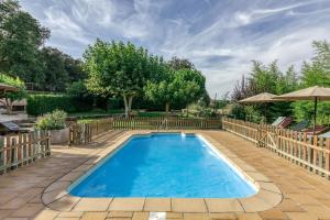 a swimming pool with a fence and an umbrella at Mas Alba in San Esteban de Guialbes
