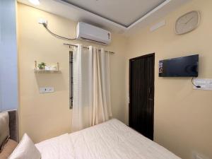 a bedroom with a bed and a tv on the wall at Faaloon 102 in Chennai