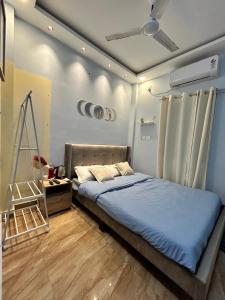 a bedroom with a bed with blue sheets and a ceiling at Faaloon 102 in Chennai