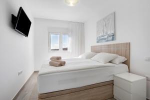 a bedroom with a large white bed with a television at Casa Helieta in Puerto del Rosario