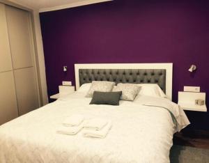 a purple bedroom with a large bed with two towels on it at O Cantón in La Bola