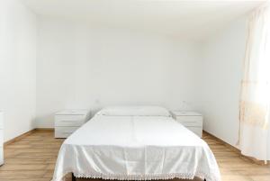 a white bedroom with a white bed and a window at Enjoy The Silence Flat in Orosei